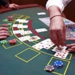 Blackjack table and hands of dealer and player playing a variation of blackjack.