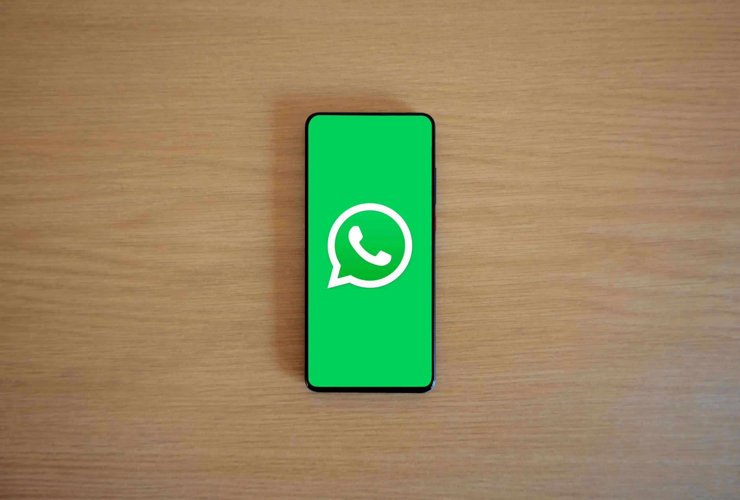 WhatsApp's logo against a green background, which fills up a smartphone screen.