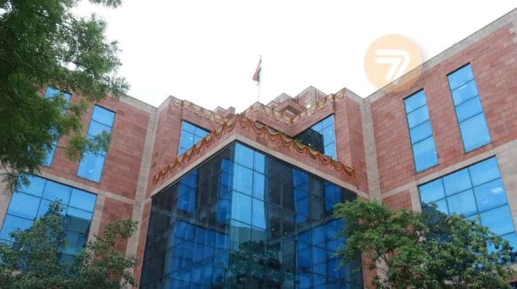 A modern building with a sleek red brick and blue glass design, with India's flag on top: the DGGI's new facility in Dwarka, Gujarat.