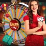 A live host holds two nine cards before the Crazy Time money wheel. Dice, chips, and a hot-air balloon fly around the host.